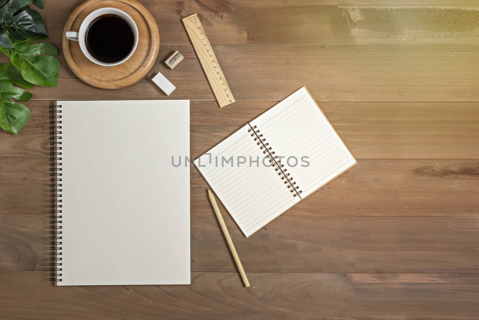 Flat lay of wooden office desk table with blank notebook, supplies and coffee cup. Top view with copy space.