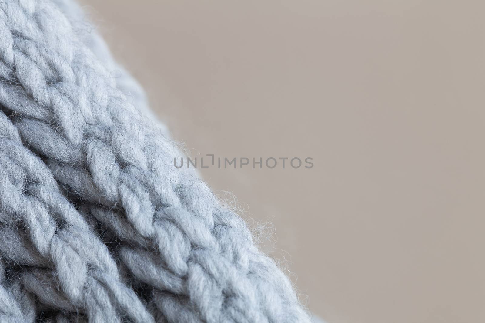 Knitted woolen textured surface on beige background. Macro. Soft grey merino wool pattern backdrop, closeup. Autumn and winter flat lay. Scandinavian minimal style. Horizontal.