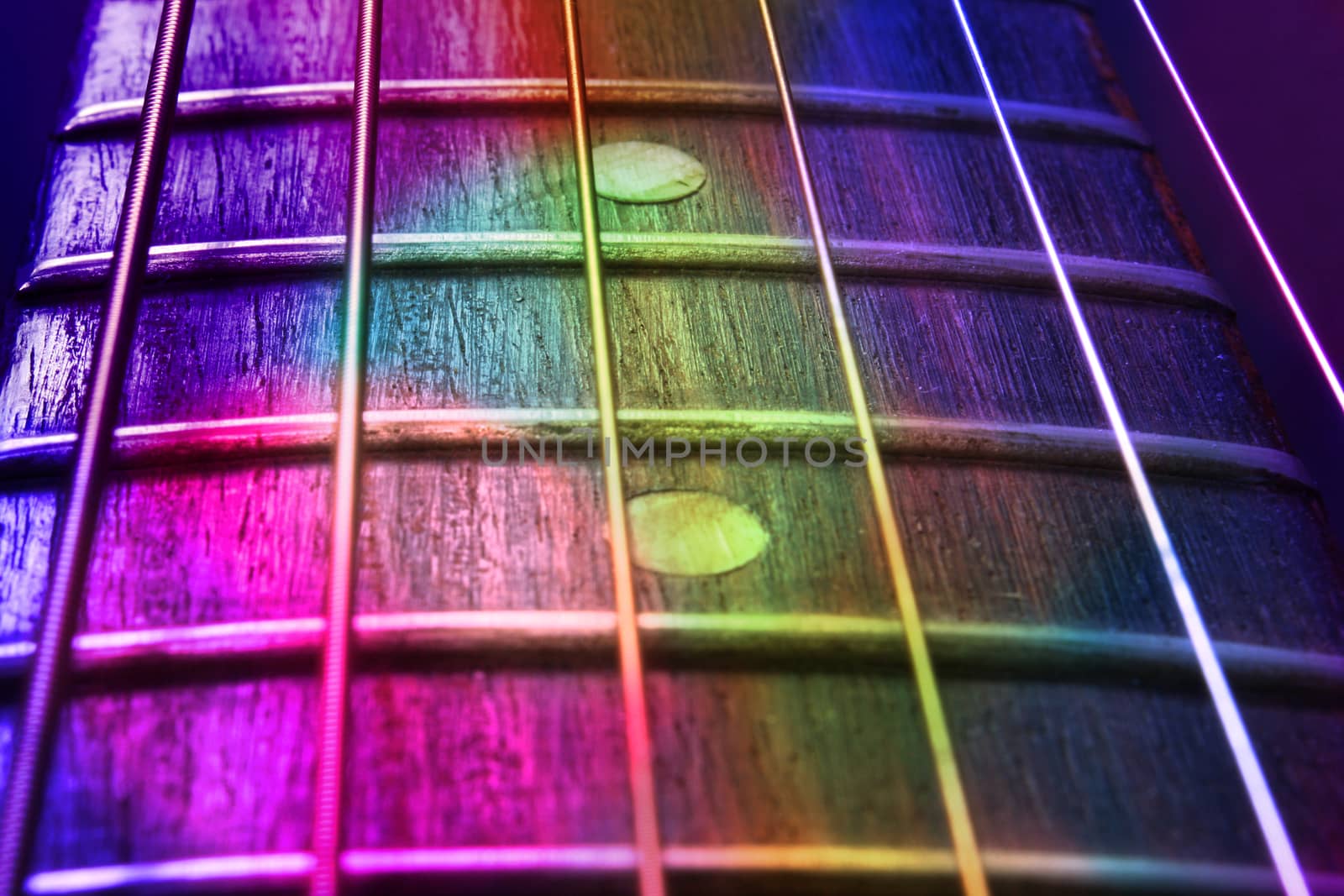 An abstract background of a guitar fretboard and strings in colorful lights. 