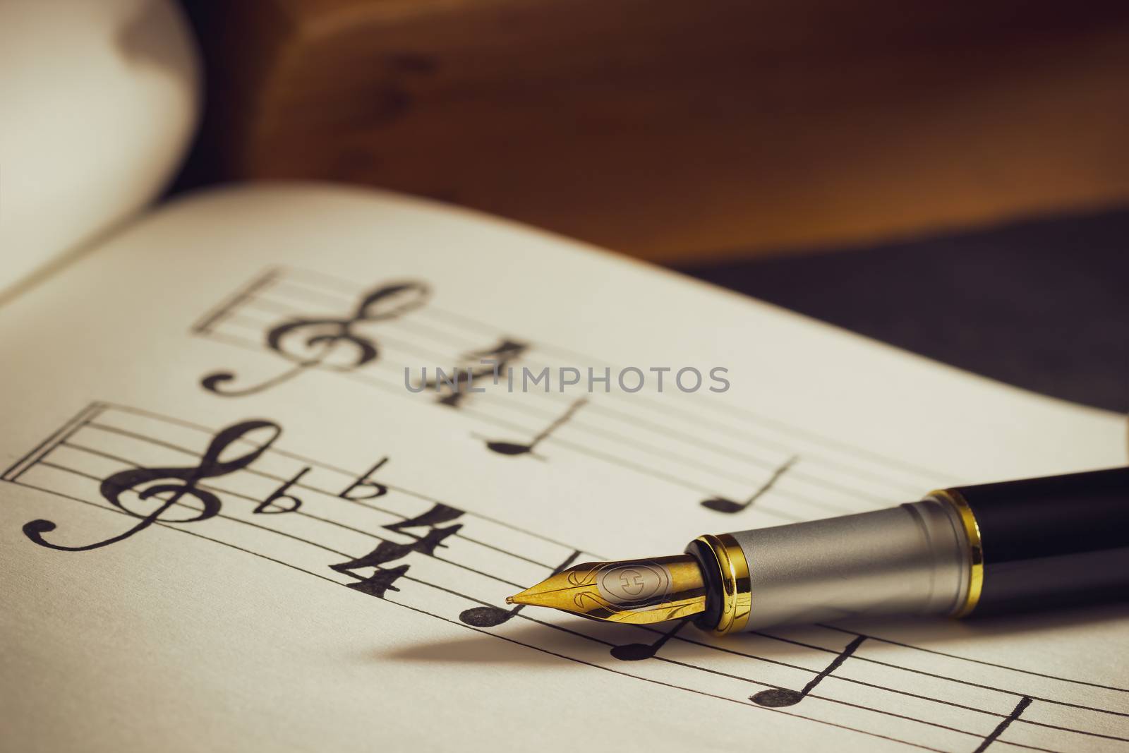 Music notes and old book on wooden table background in morning light. Writing chords by vintage pen. Closeup and copy space for text. Concept of Music lovers.