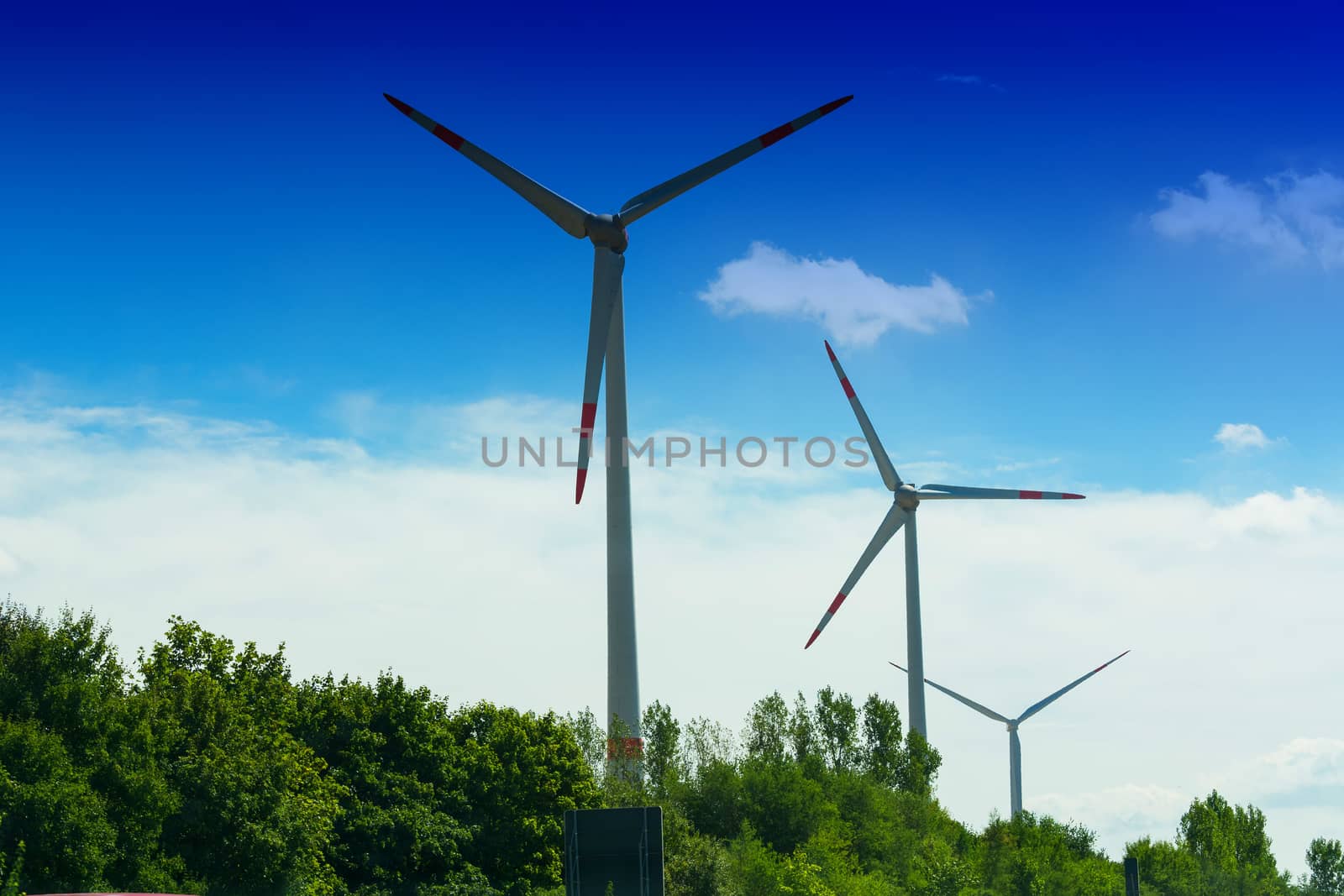 Windmill turbines with partially cloudy blue sky in the background. Wind turbines for renewable energies