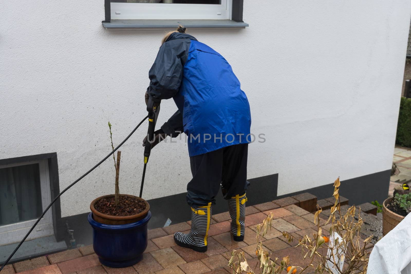 Woman cleans stone slabs with a pressure washer