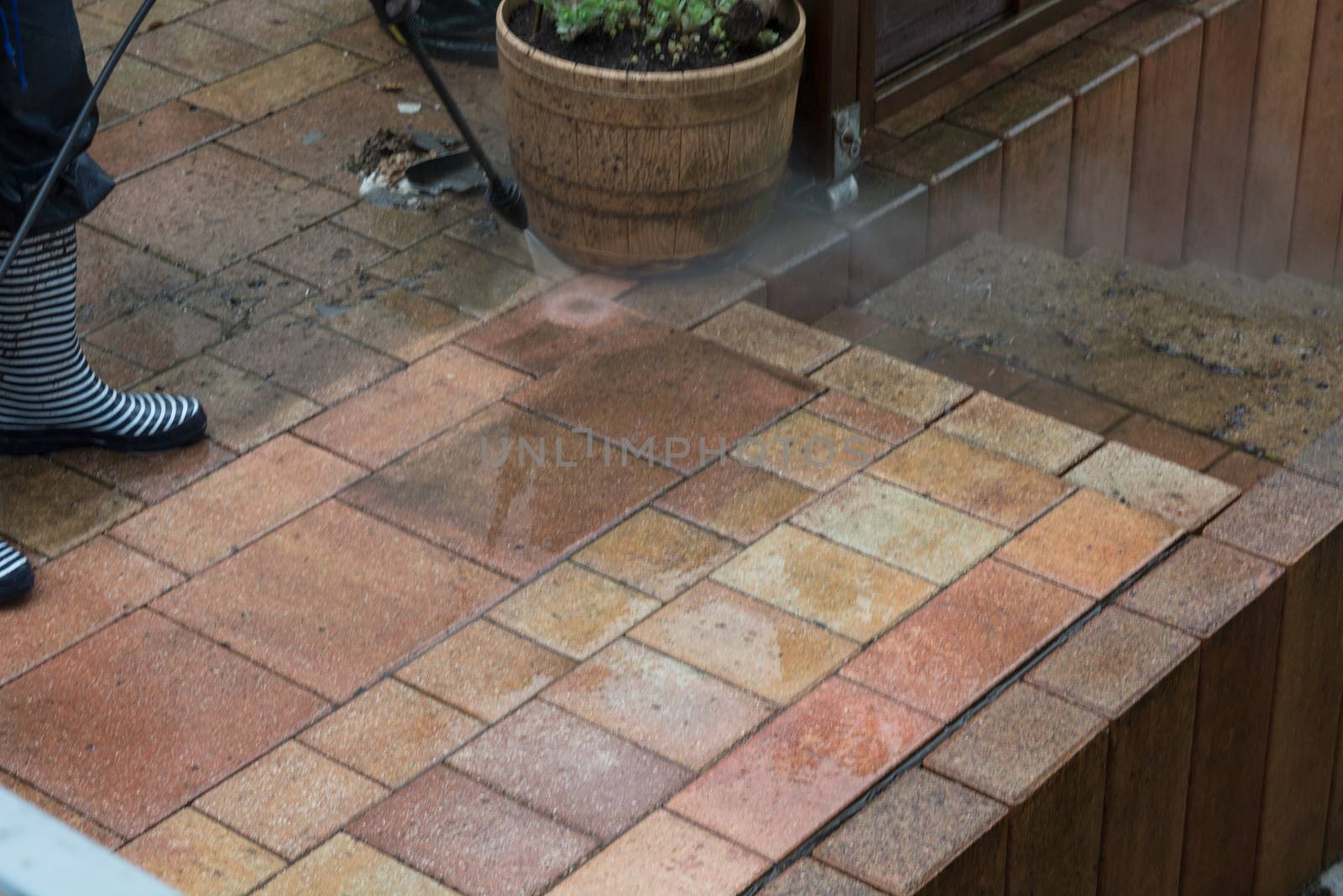 Woman cleans stone slabs with a pressure washer