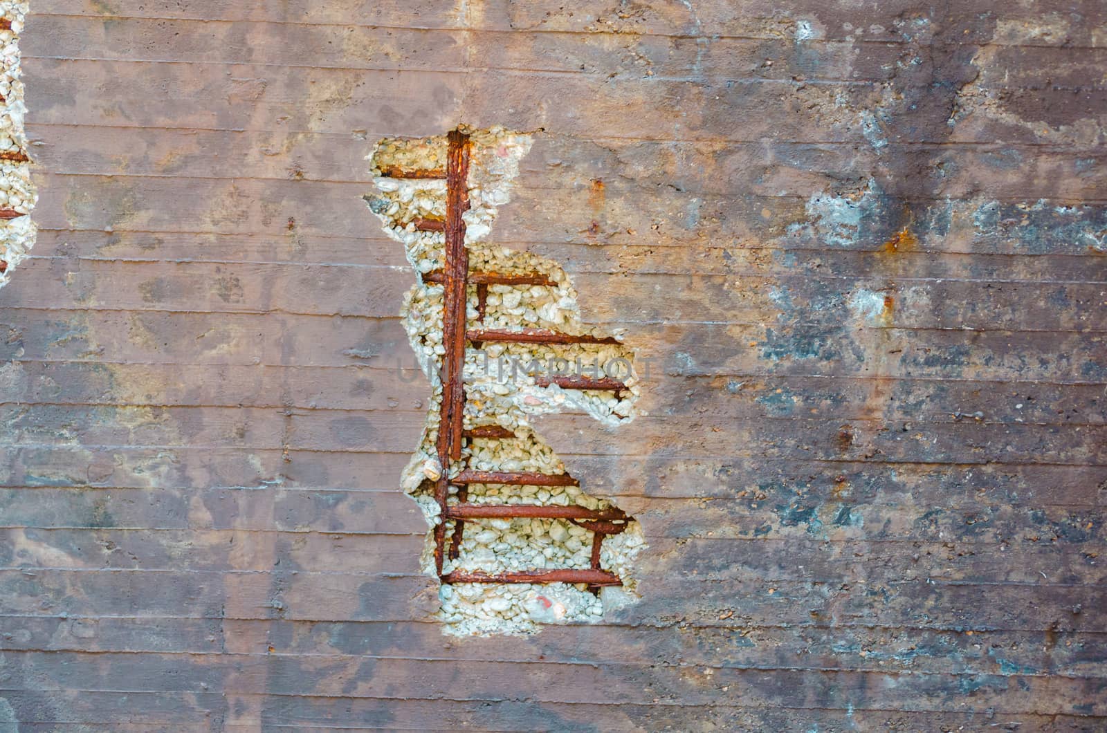 Old weathered broken concrete wall with rusty ironiron