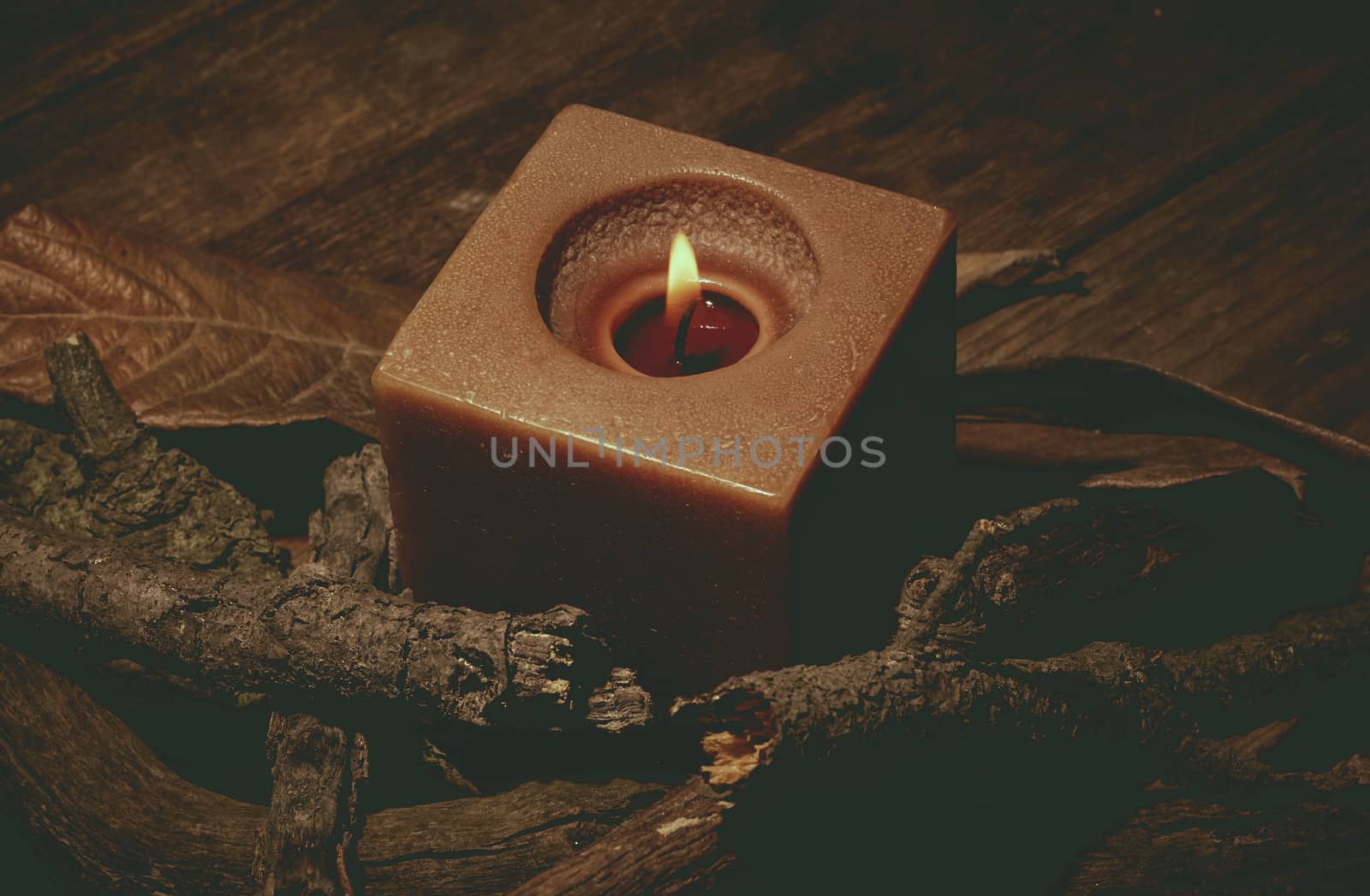 candle in darkness with pieces of wood in brown