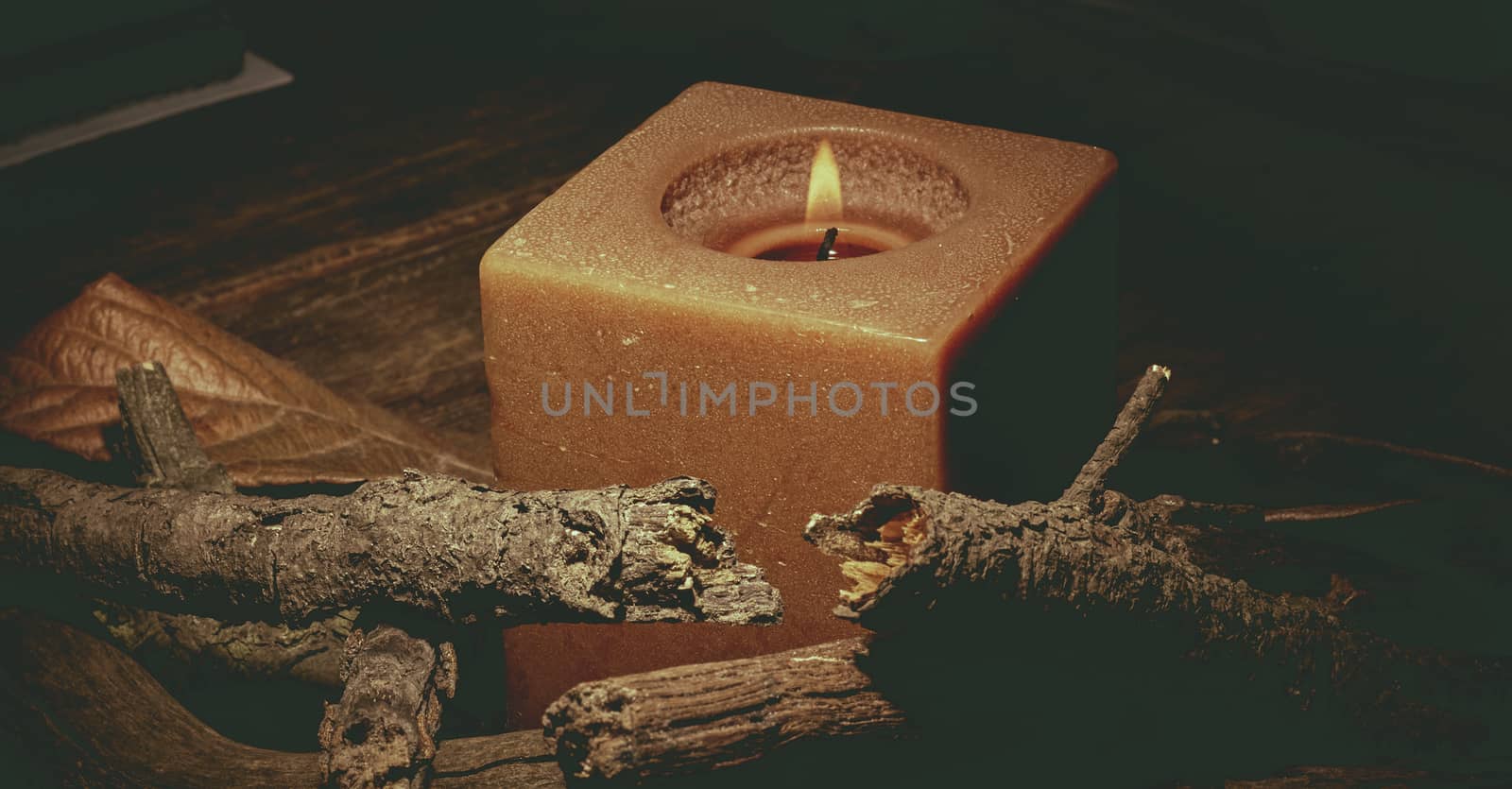 candle in darkness with pieces of wood in brown