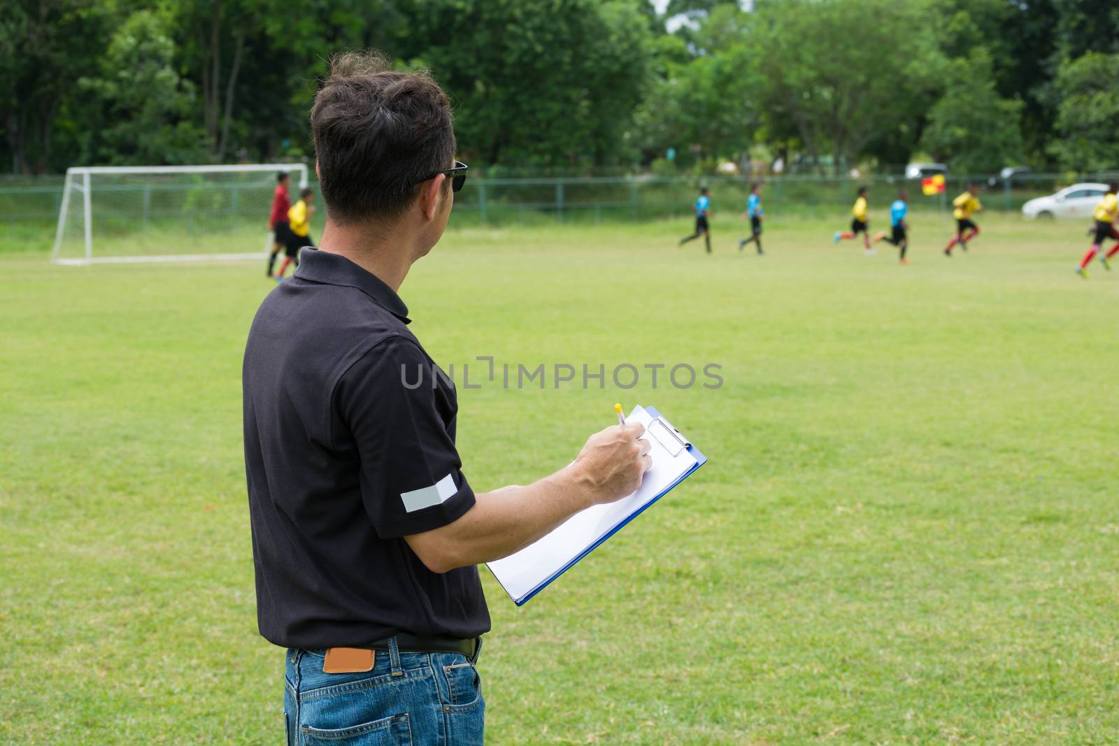 Team Manager Coaching his Crew beside Football or Soccer Field by thampapon