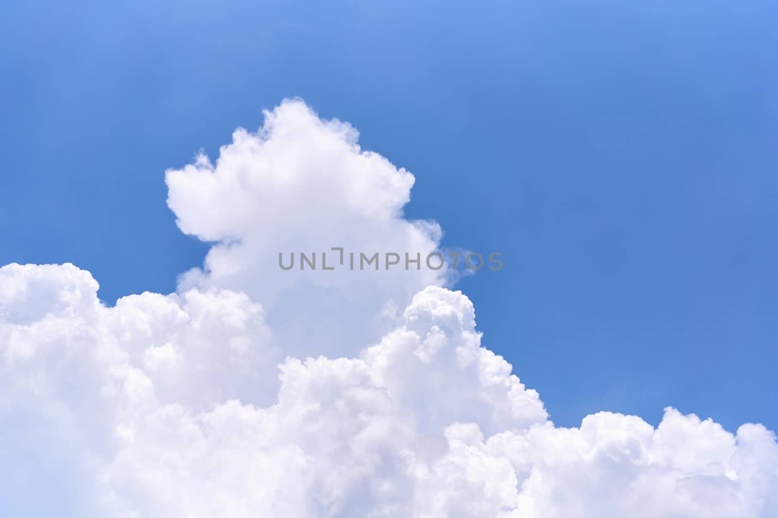 White puffy cumulus cloud on the blue sky as background with copy space.