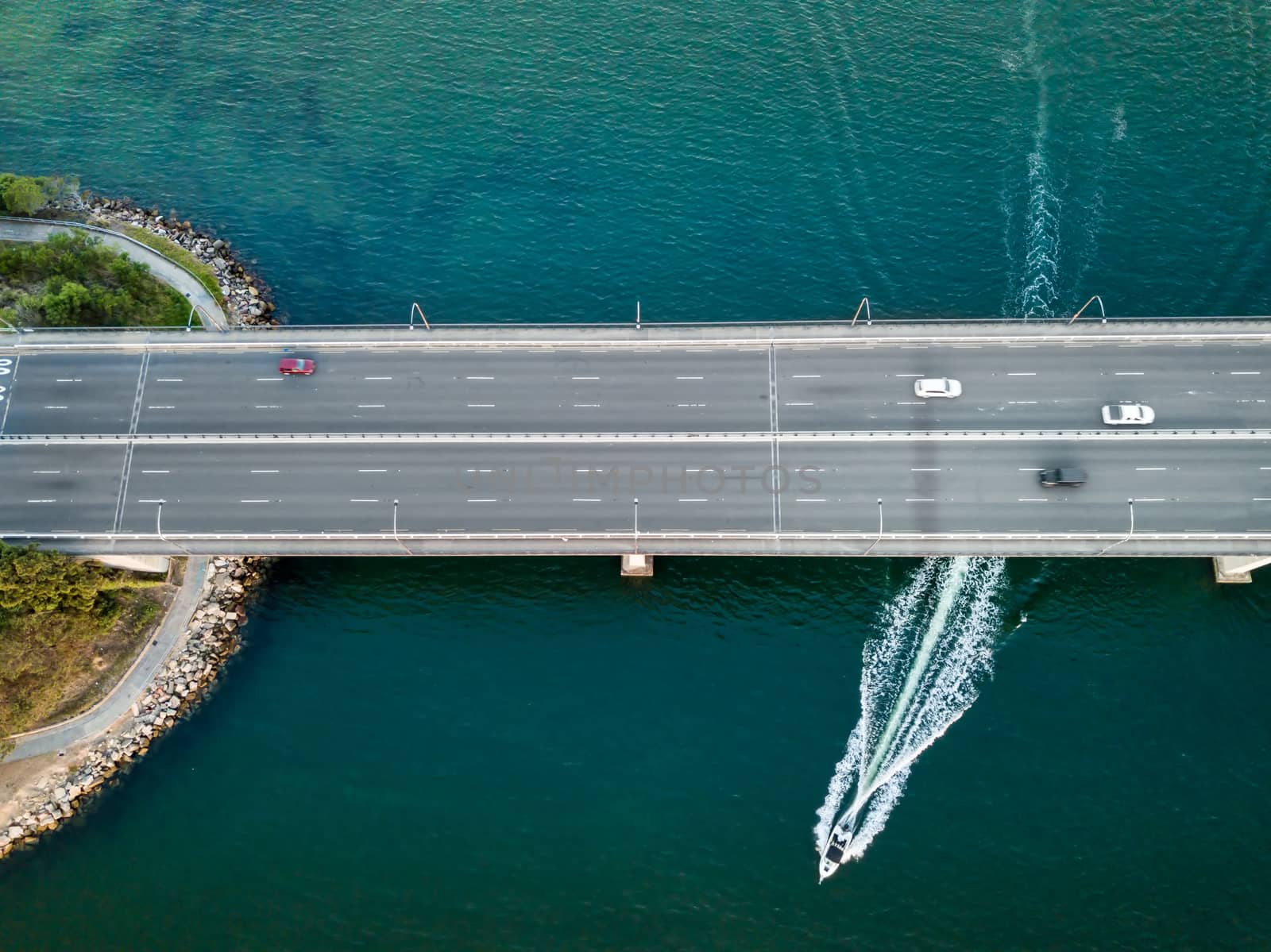 Cars on Captain Cook Bridge and a speed boat underneath it on Georges River