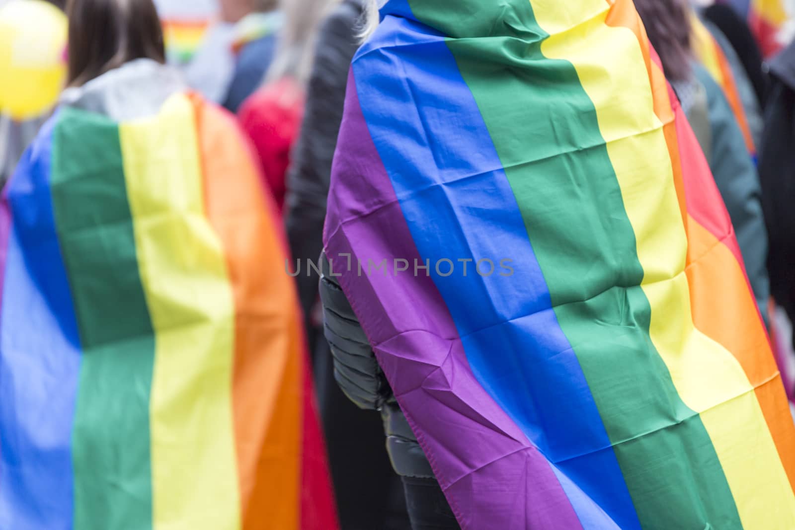 Person Carrying Rainbow Flag over Sholders in Pride Parade.