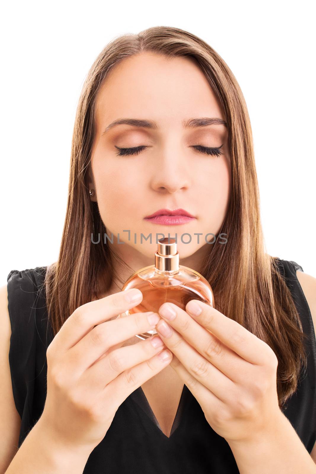 Close up of a beautiful young woman holding a perfume bottle, smelling the perfume scent with eyes closed, isolated on white background.