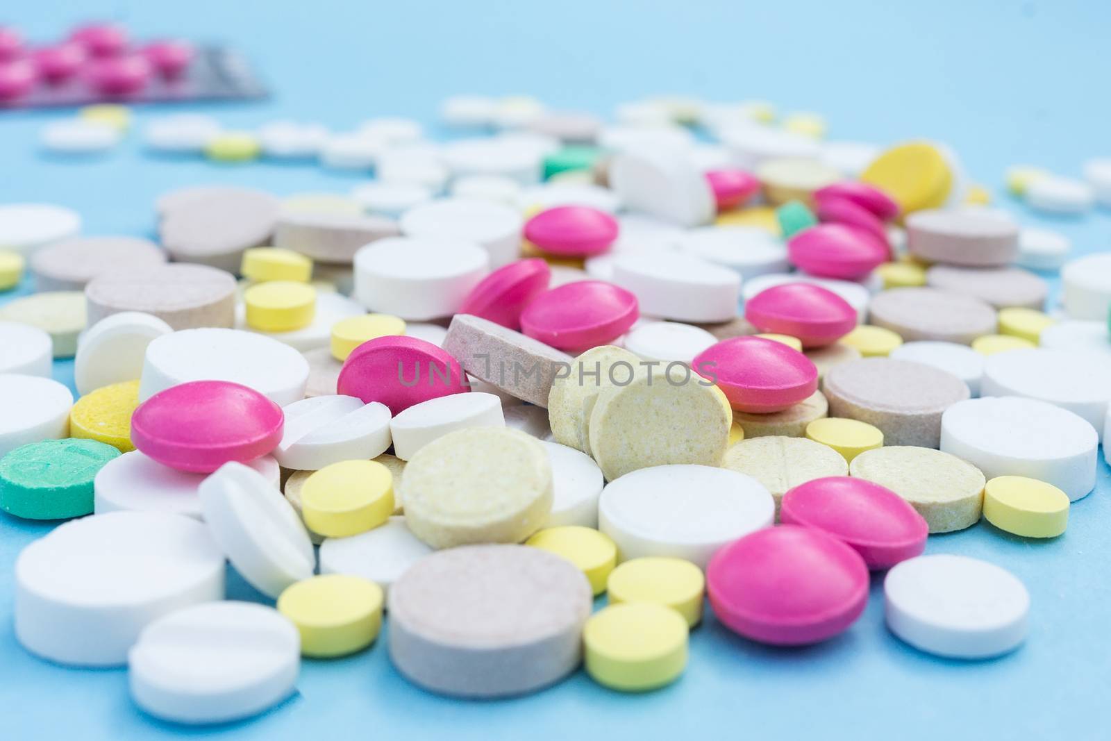 Assorted pharmaceutical medicine pills, tablets and capsules over blue background