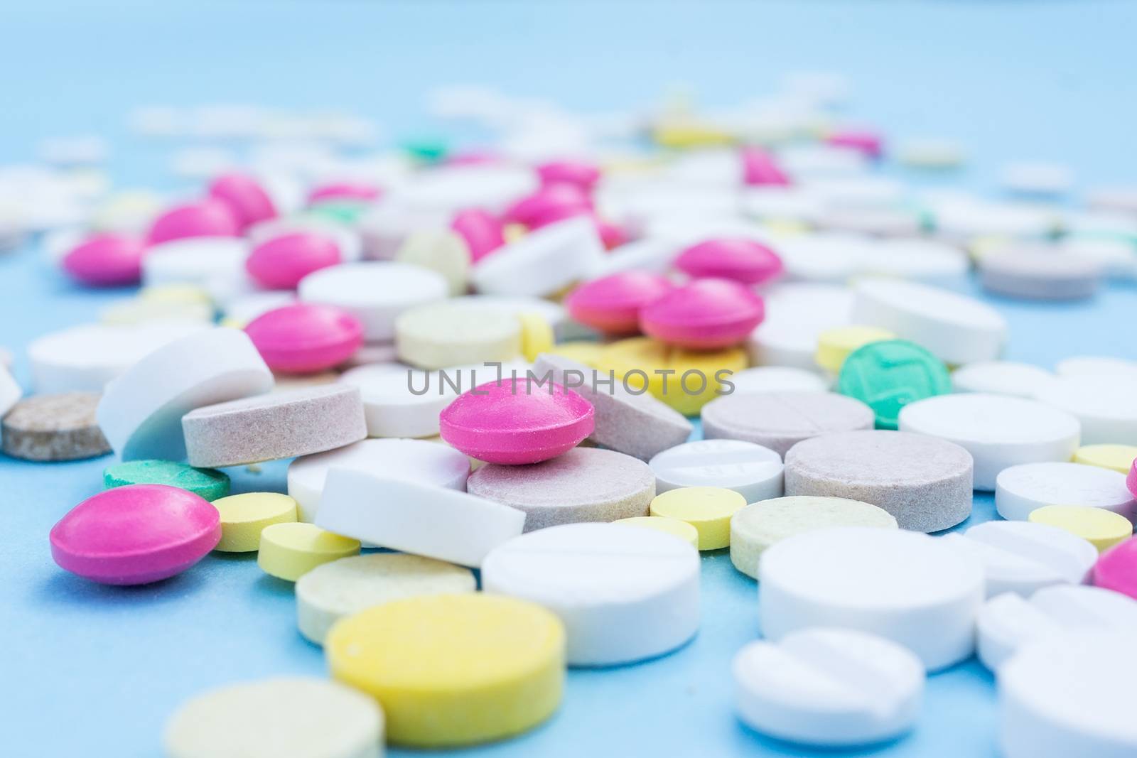 Assorted pharmaceutical medicine pills, tablets and capsules over blue background