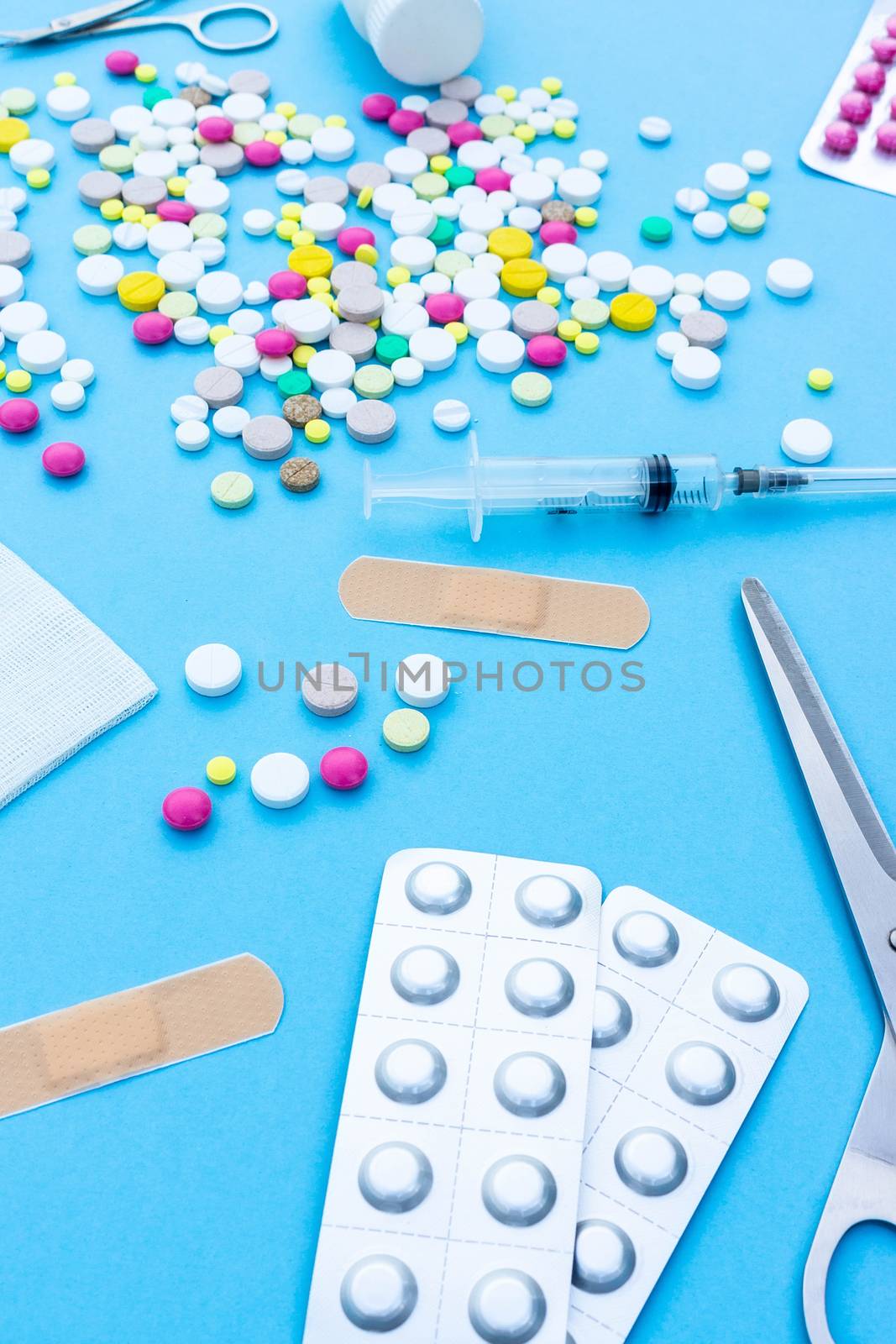 Assorted pharmaceutical medicine pills, tablets and capsules over blue background