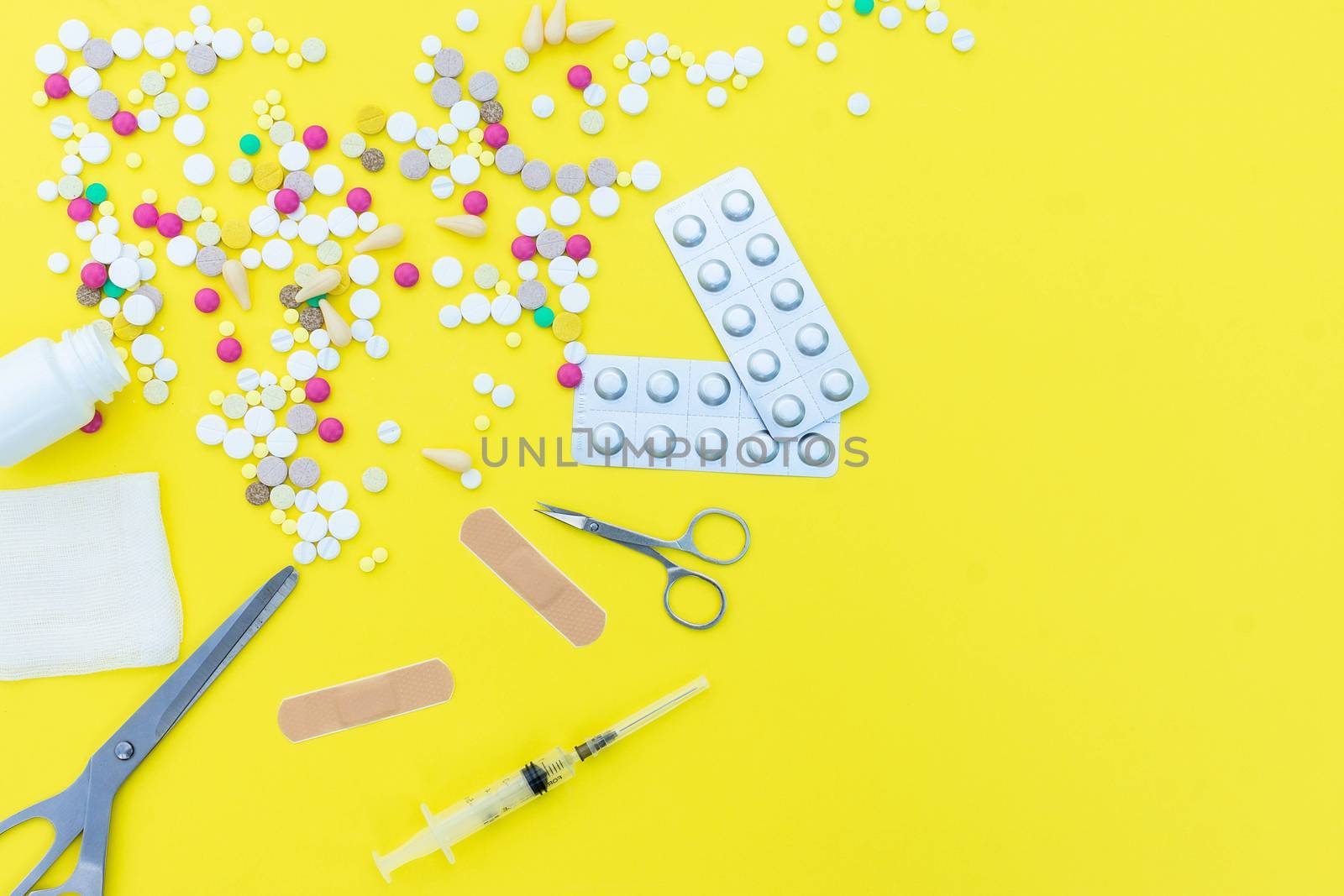 Assorted pharmaceutical medicine pills, tablets and capsules over yellow background