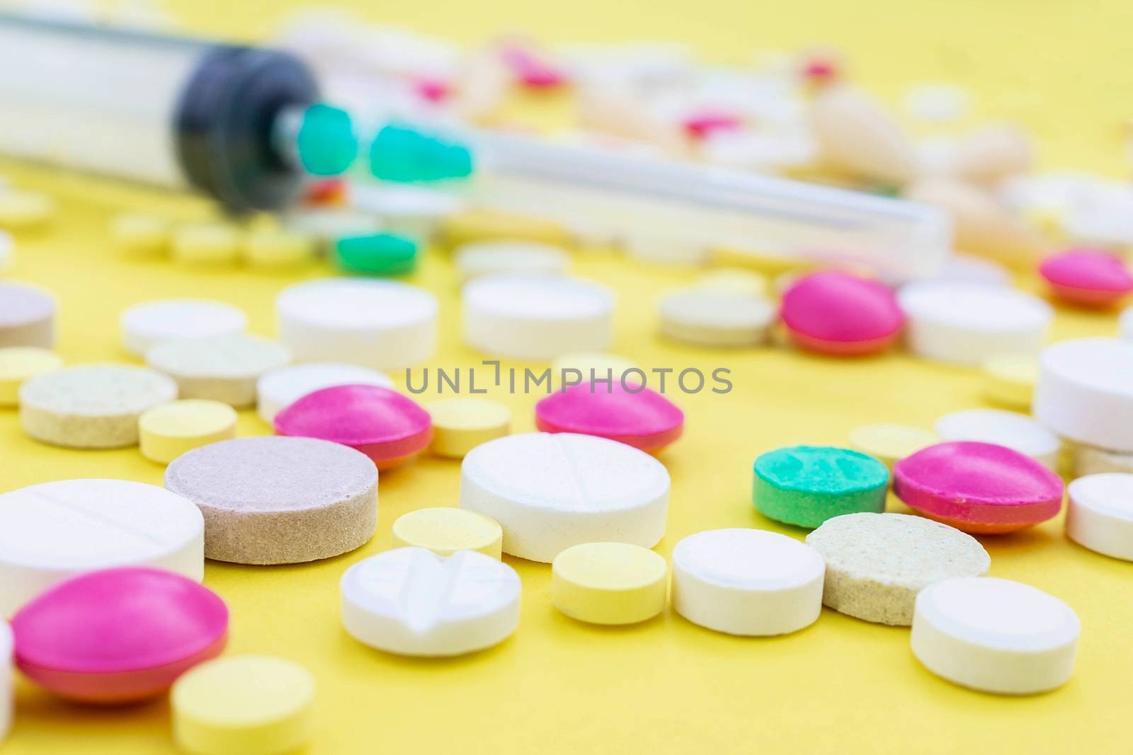Assorted pharmaceutical medicine pills, tablets and capsules over yellow background