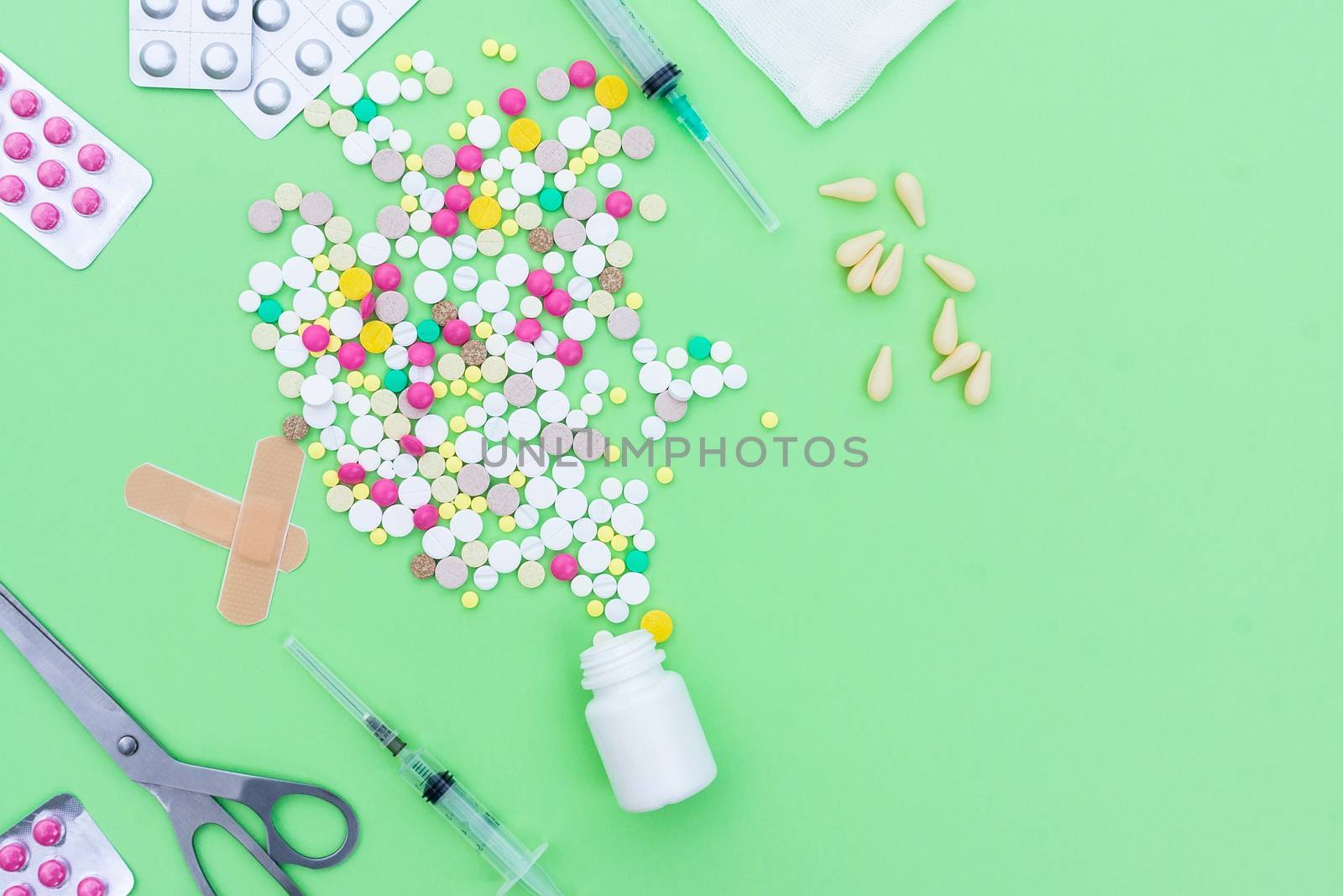 Assorted pharmaceutical medicine pills, tablets and capsules over green background