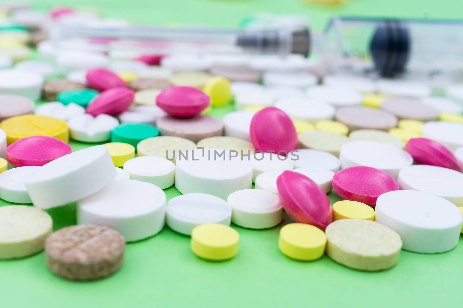 Assorted pharmaceutical medicine pills, tablets and capsules over green background