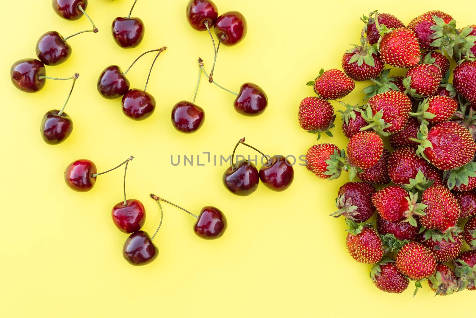 fresh strawberries and cherries on a yellow background