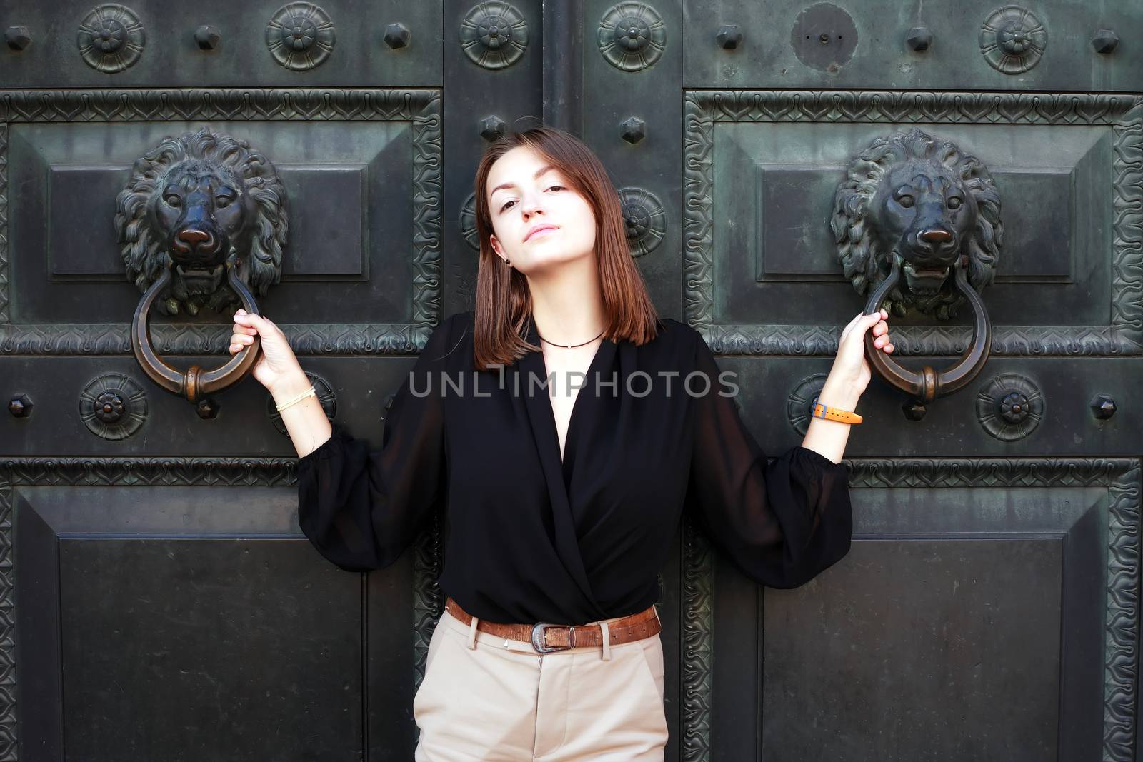 Beautiful young woman near old iron building door