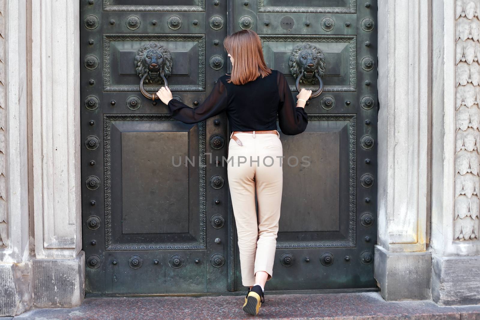 Beautiful young woman near old iron building door