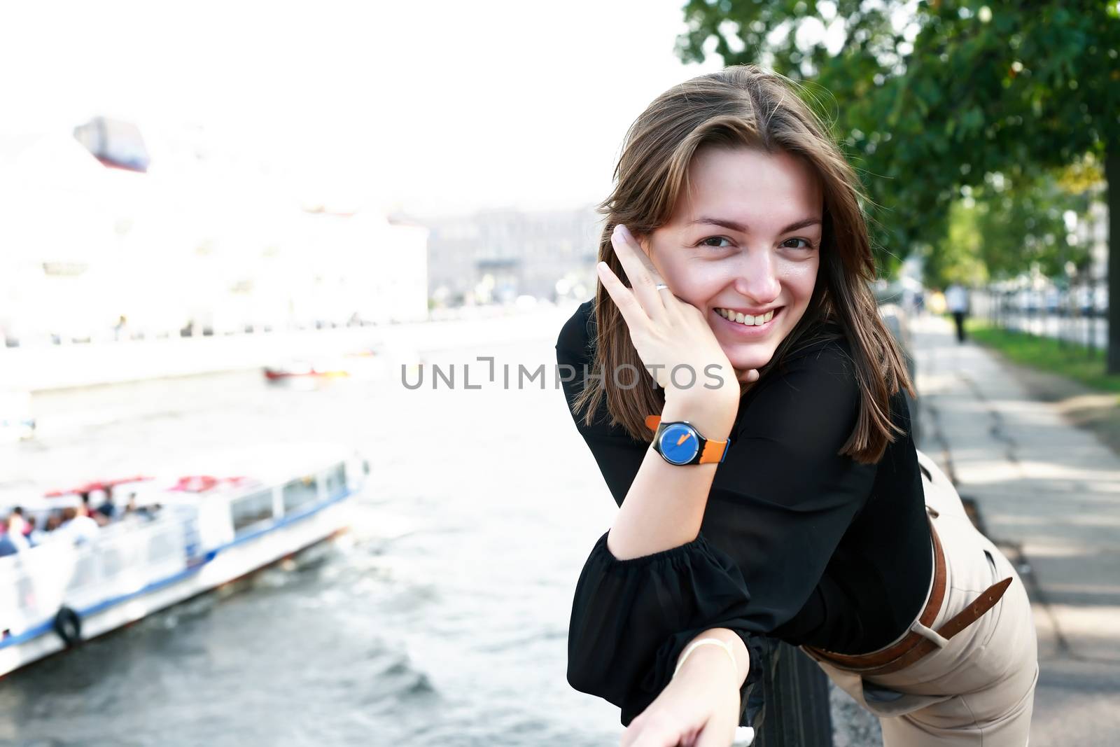 Beautiful young woman on embankment near river in city