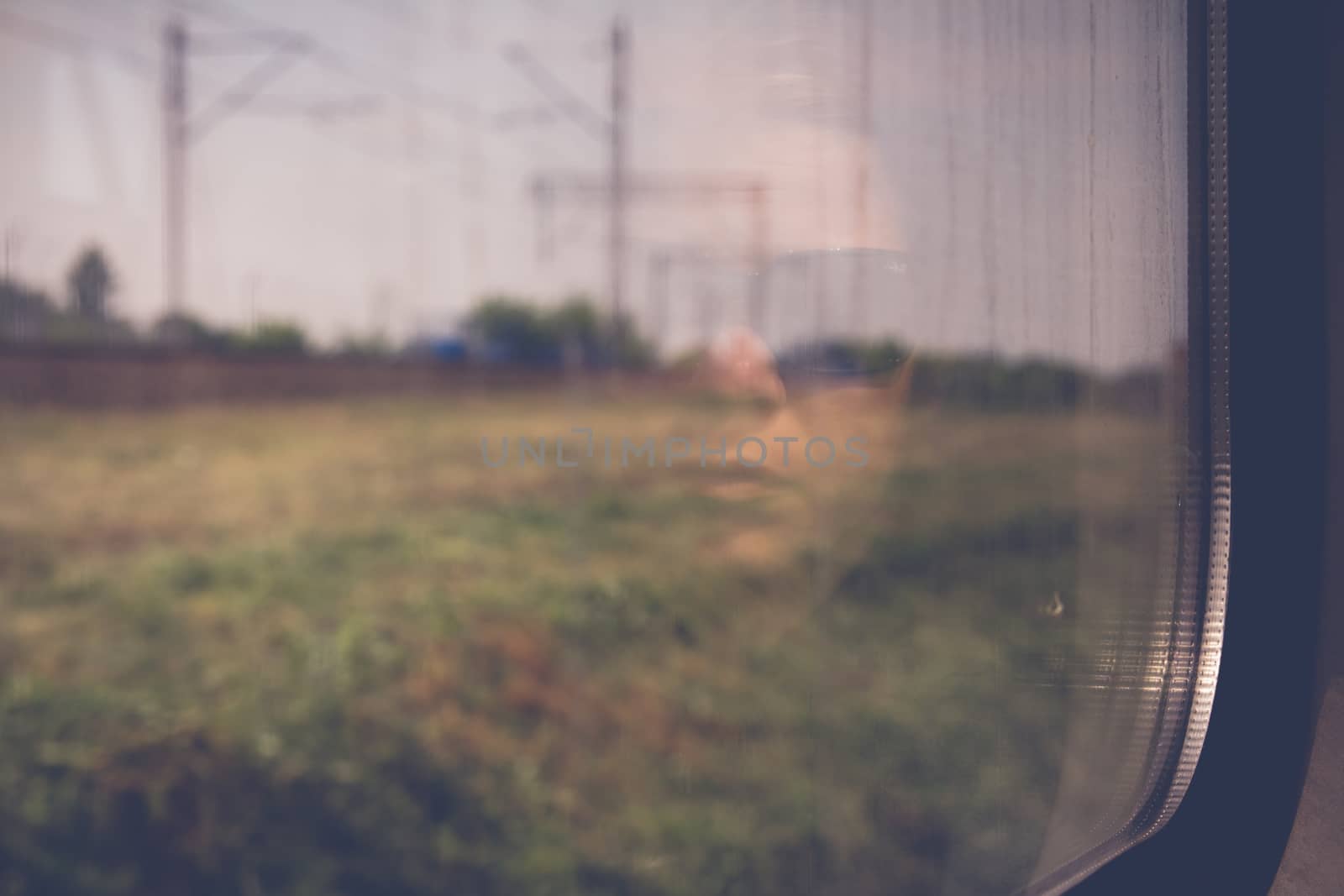 Mysterious woman face with black sunglasses reflected in the window of a traveling train. Nostalgic moment concept.