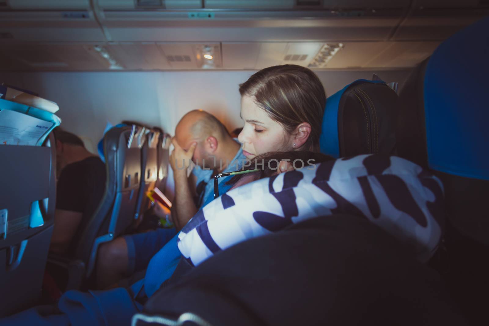 Tired caucasian men and women sleeping on seats while traveling in a commercial airplane.