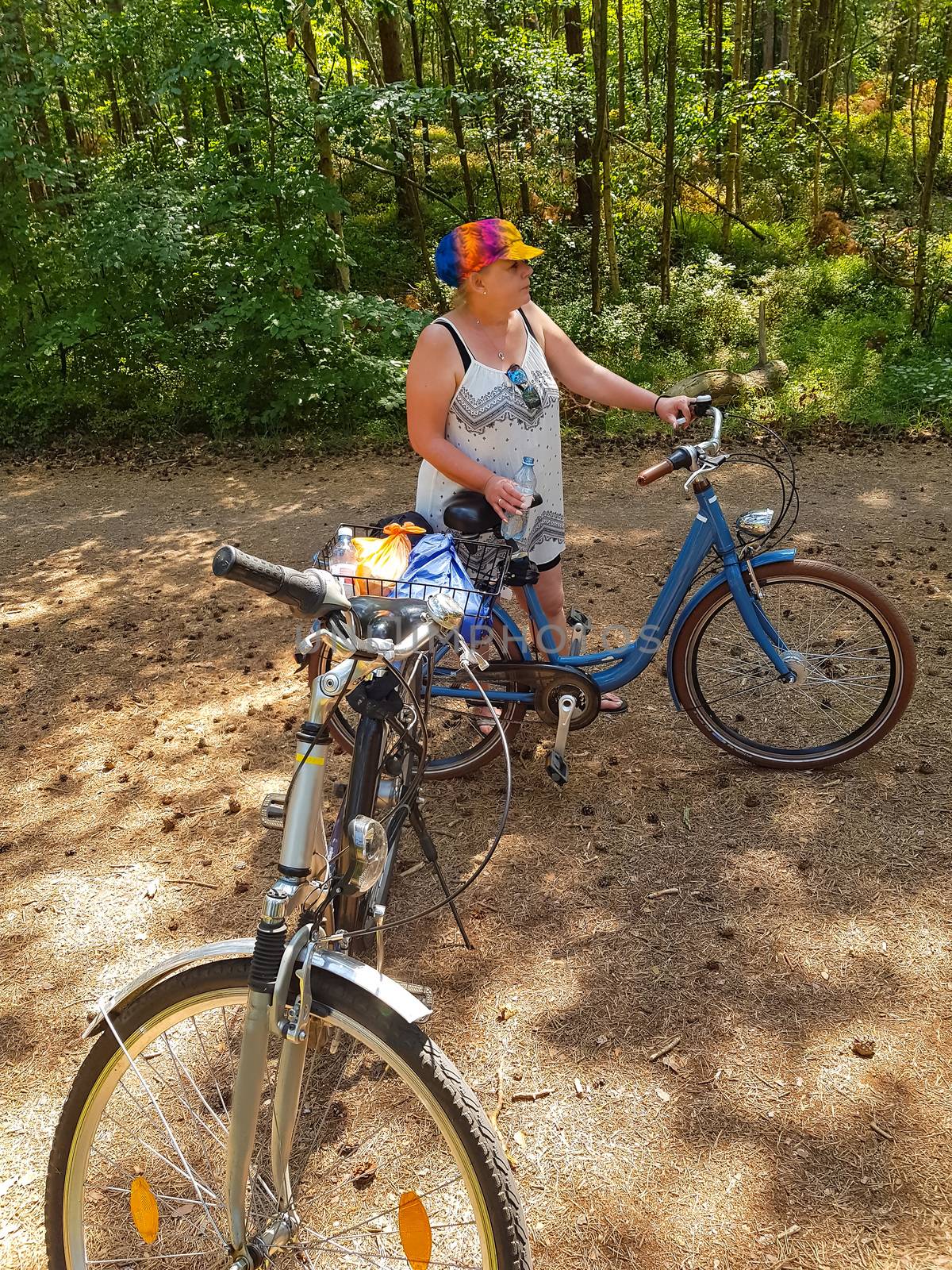 Senior beautiful woman riding a bicycle through a forest.