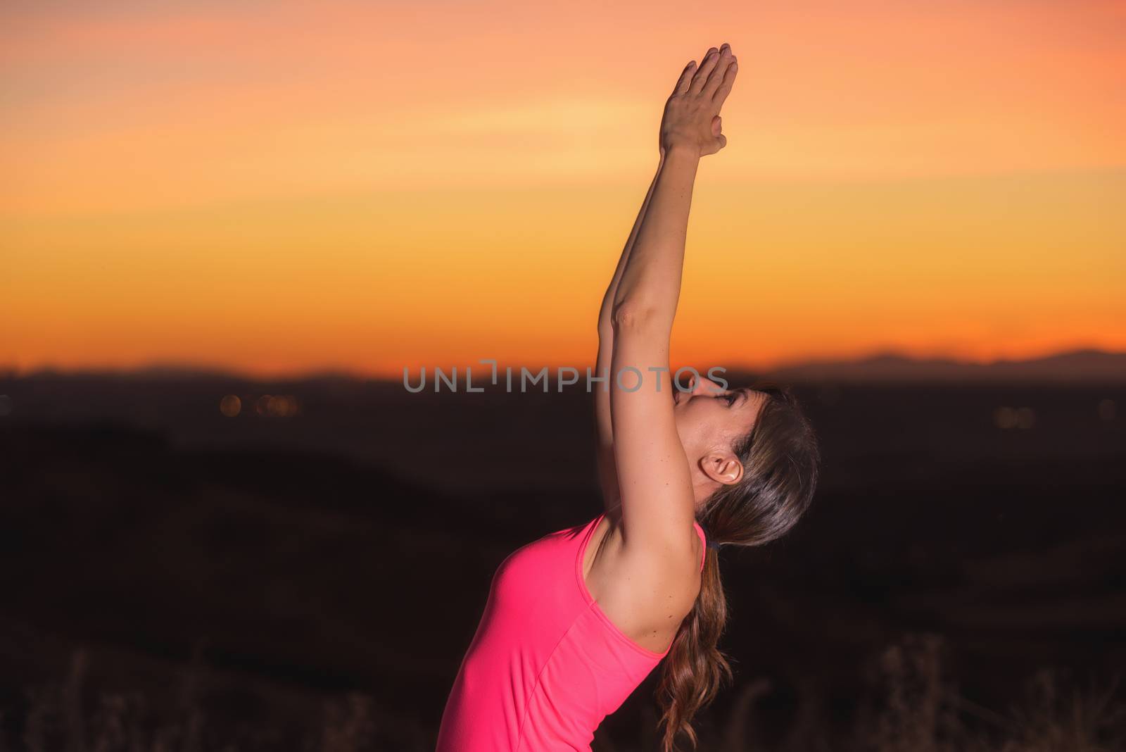 Young beautiful woman practicing Yoga at sunset