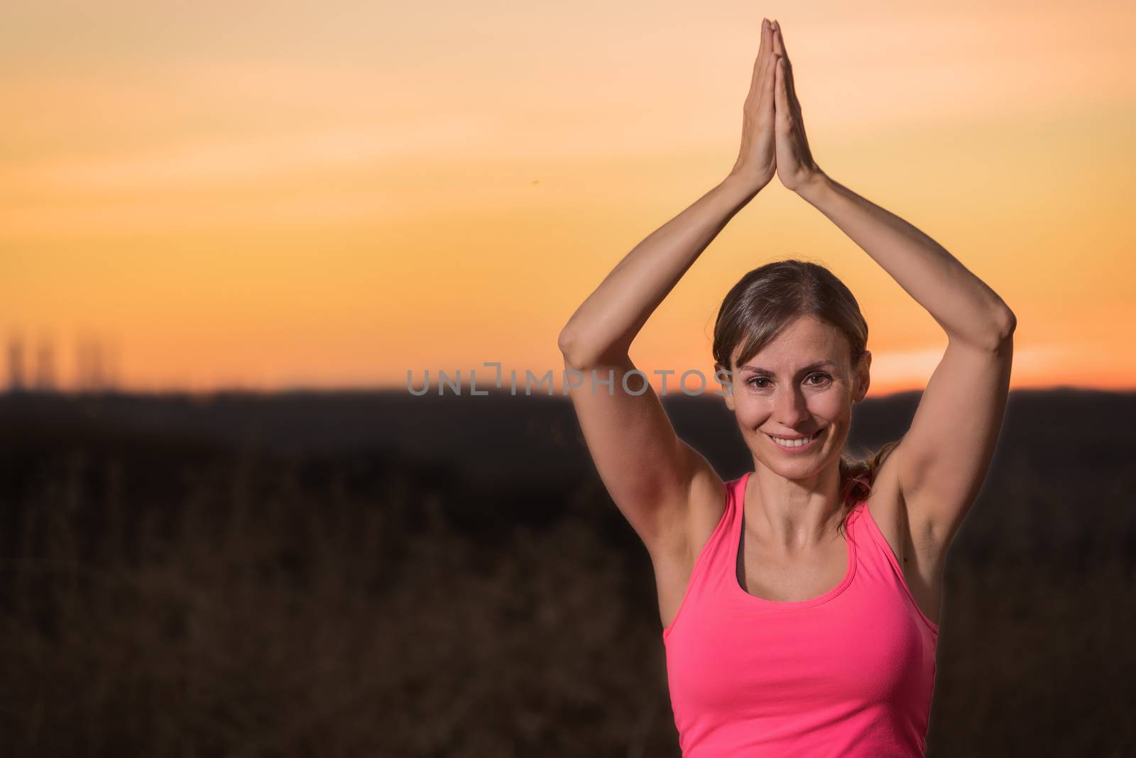Young beautiful woman practicing Yoga at sunset