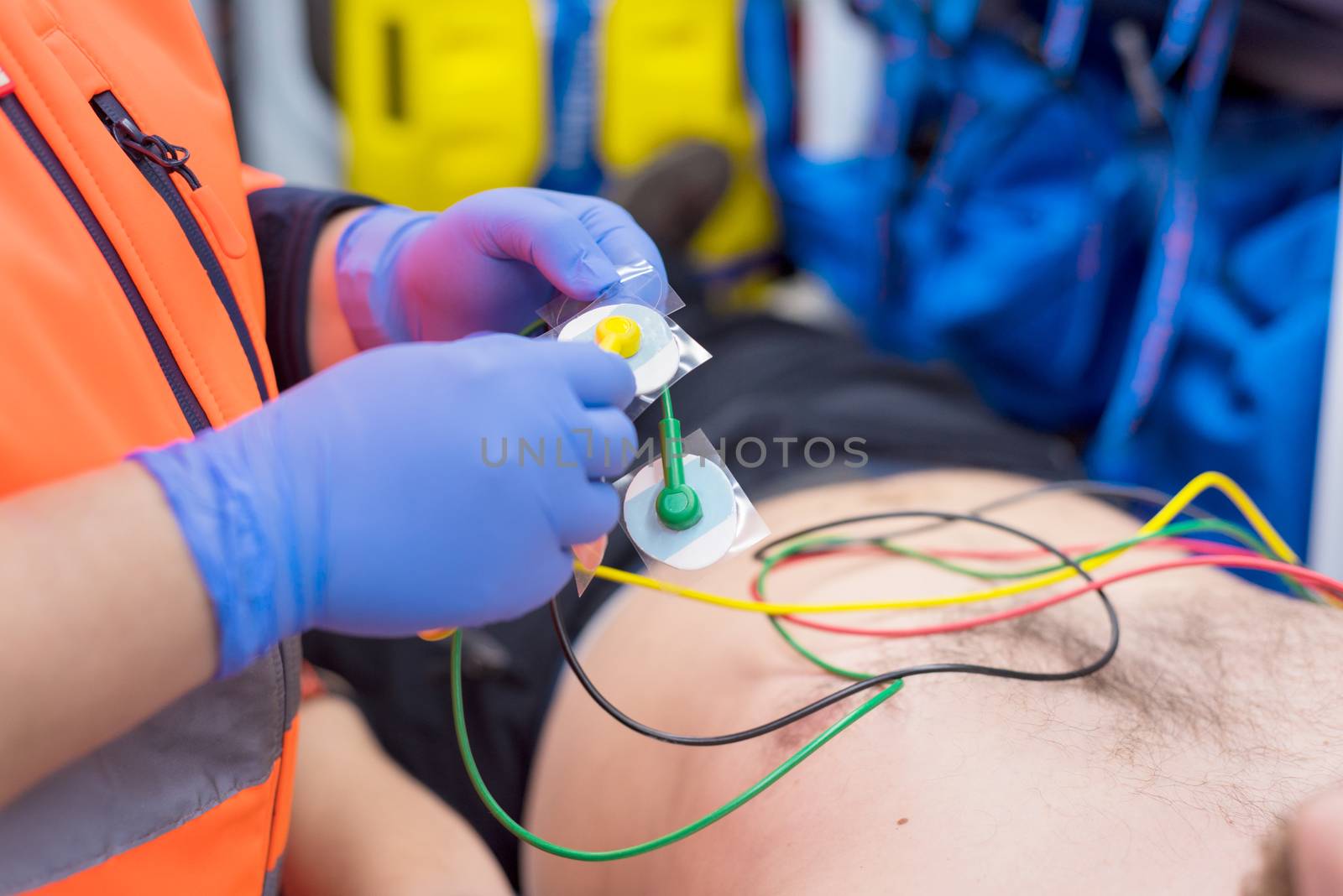 Emergency doctor hands, attaching ecg electrodes on patient chest in ambulance