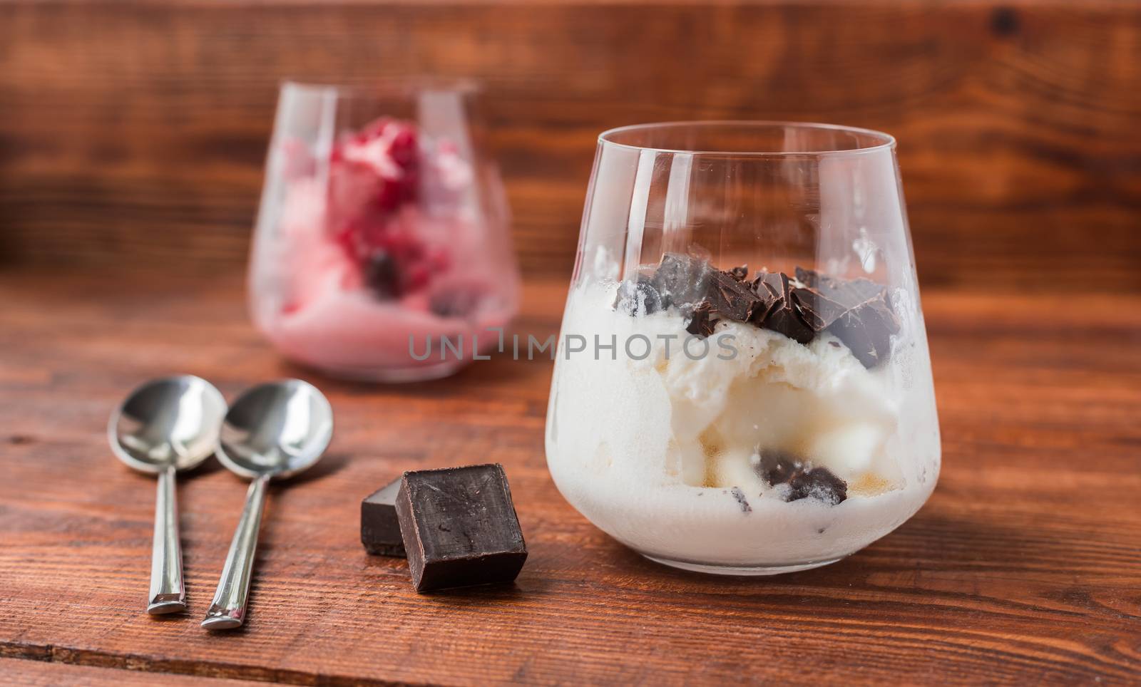 Two portions of vanilla and strawberry ice cream in glass on wooden table