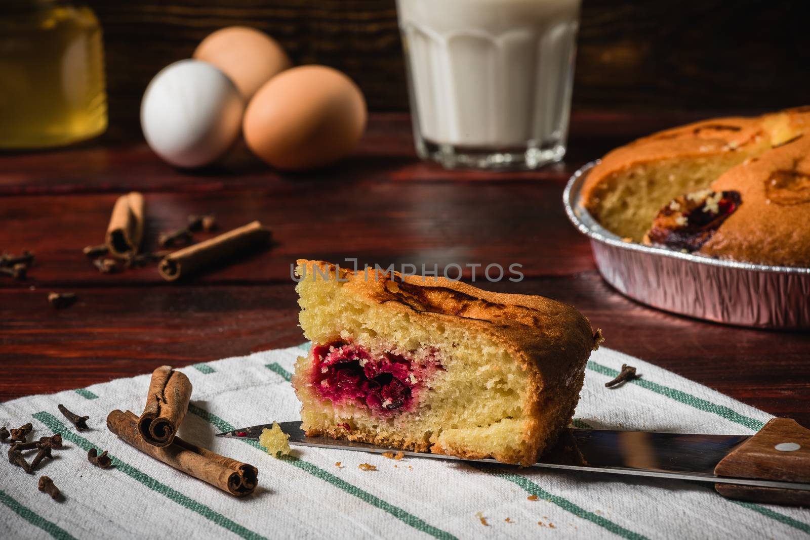 Cherry cake slice with some ingredients and spices on towel