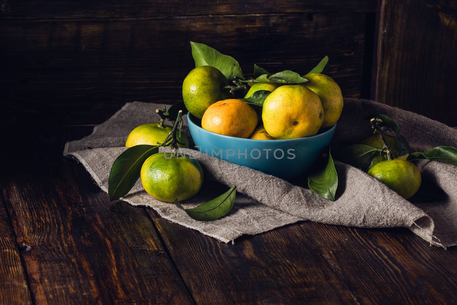 Tangerines wiyh Leaves in Blue Bowl on Dark Wooden Background.