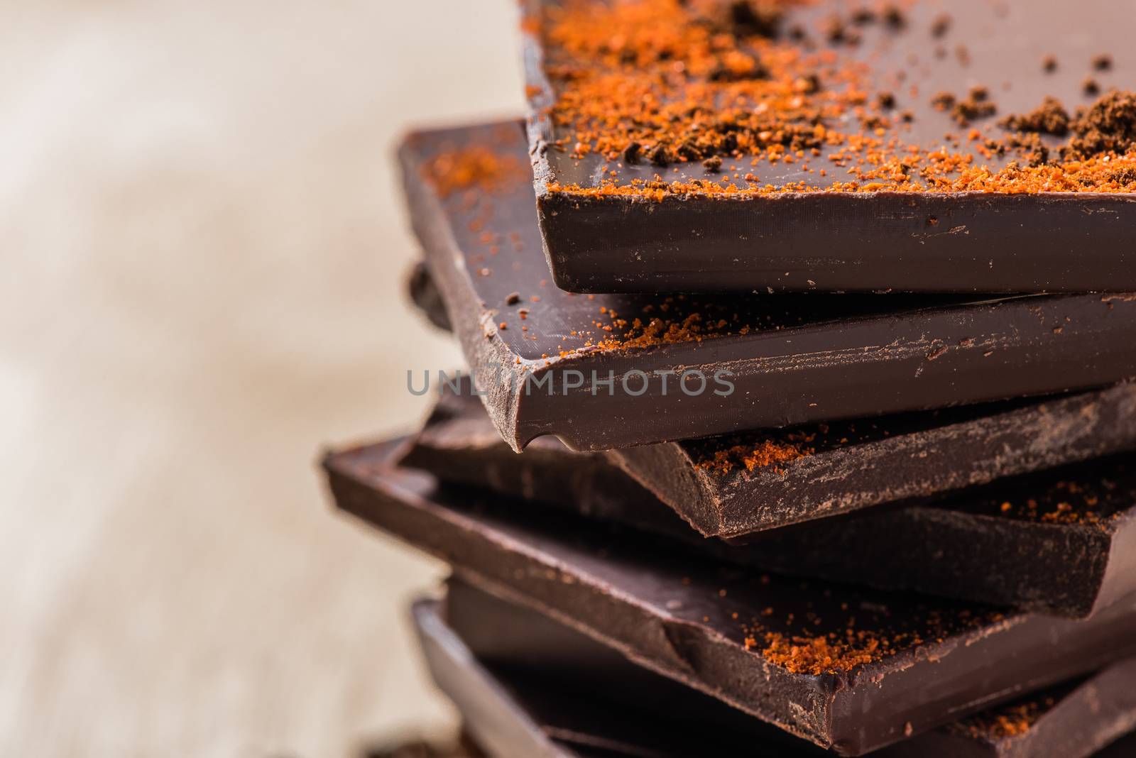 Stack of Chocolate Bars with Cayenne powder on light background
