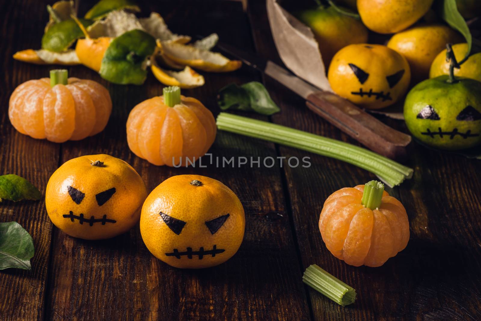 Halloween with fake pumpkins and tangerines with painted scary faces