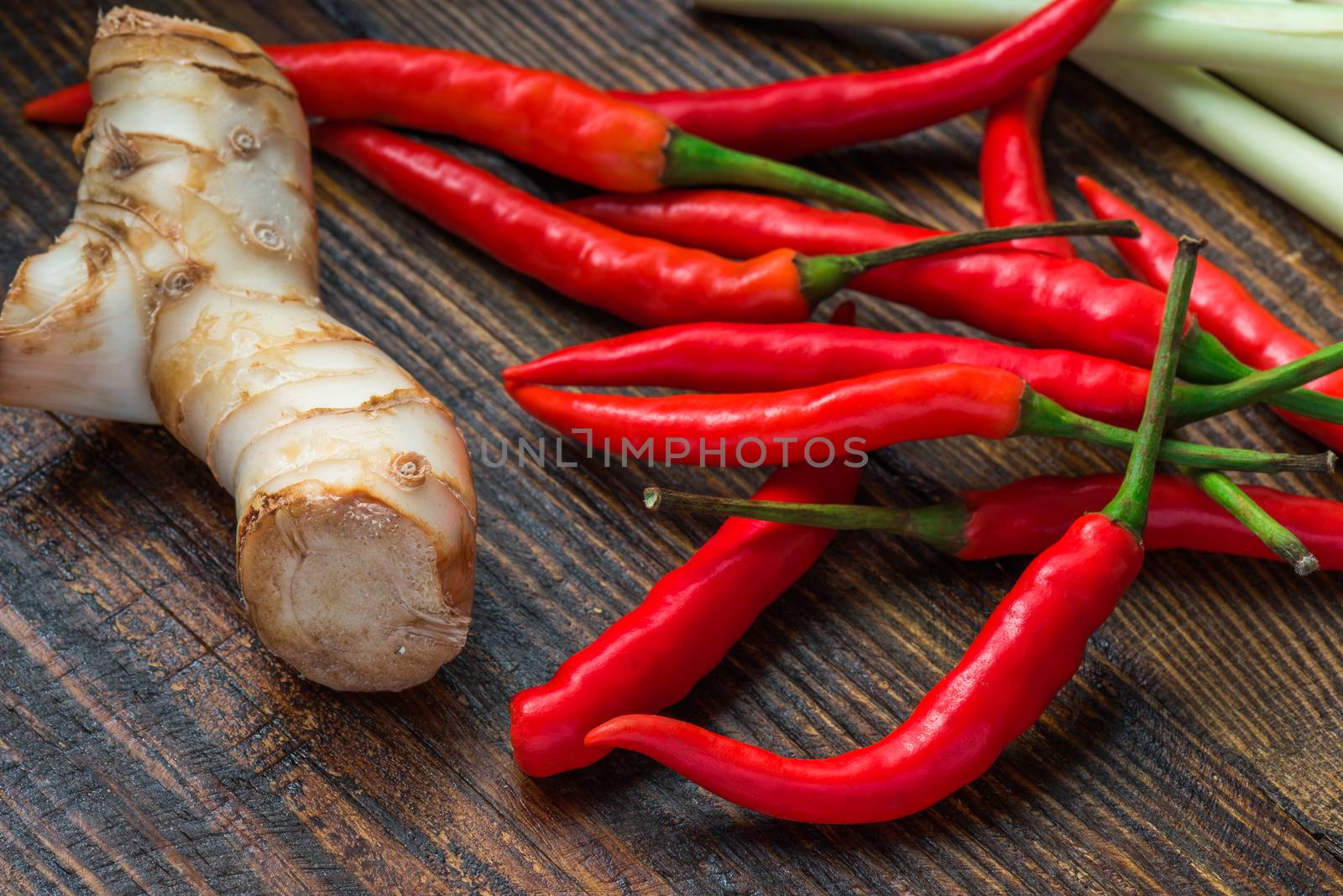 Galangal root, hot mini chili peppers with lemongrass on wooden table. 'Tom Kha Gai' soup ingredients.