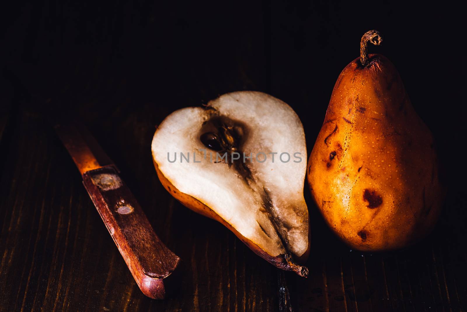 Golden Pear with Pear Half and Knife on Dark Wooden Background