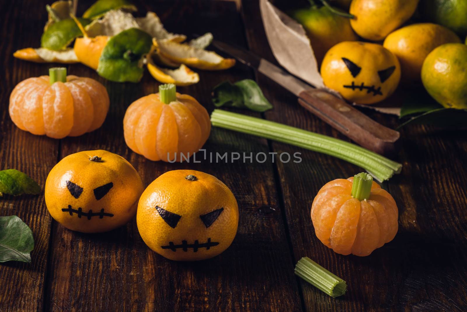 Tangerine Halloween with fake pumpkins. Painted scary faces on tangerines.