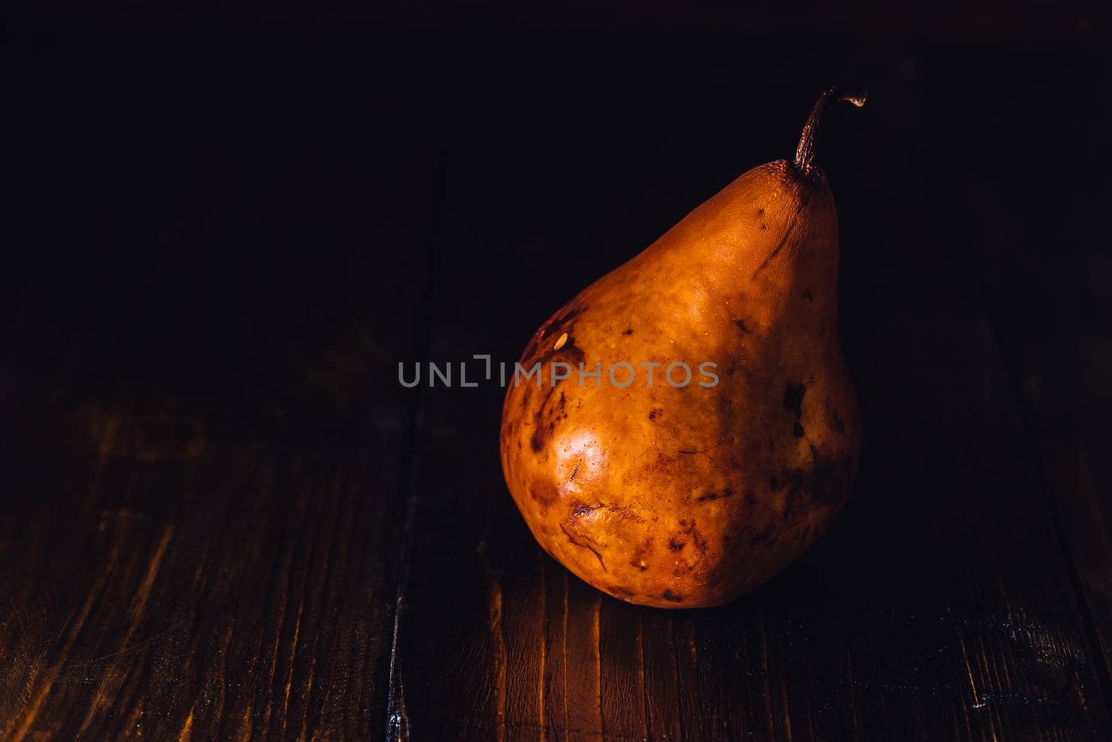 One Golden Pear on Dark Wooden Background.