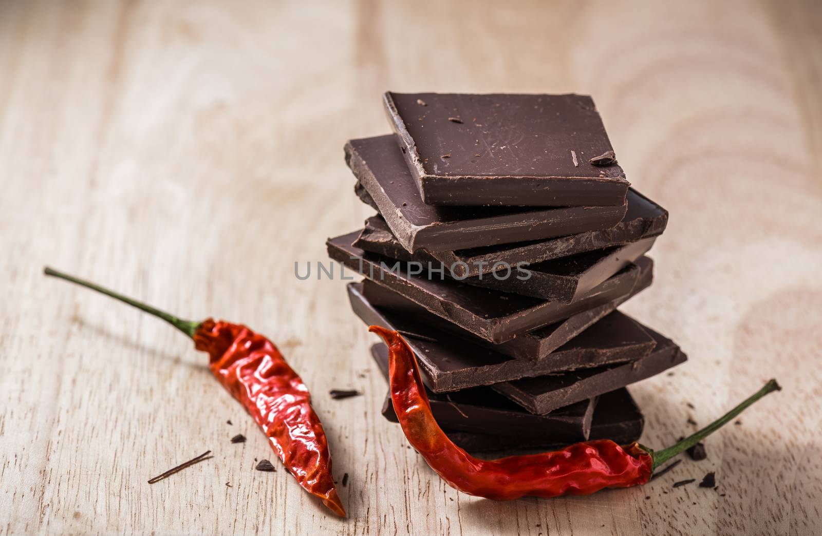 Dark Chocolate Bars Stack with Chili Peppers on Wooden Table. Place for Text.