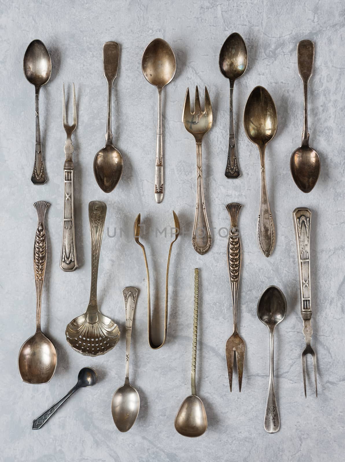 Various vintage silverware on a background of gray concrete surface