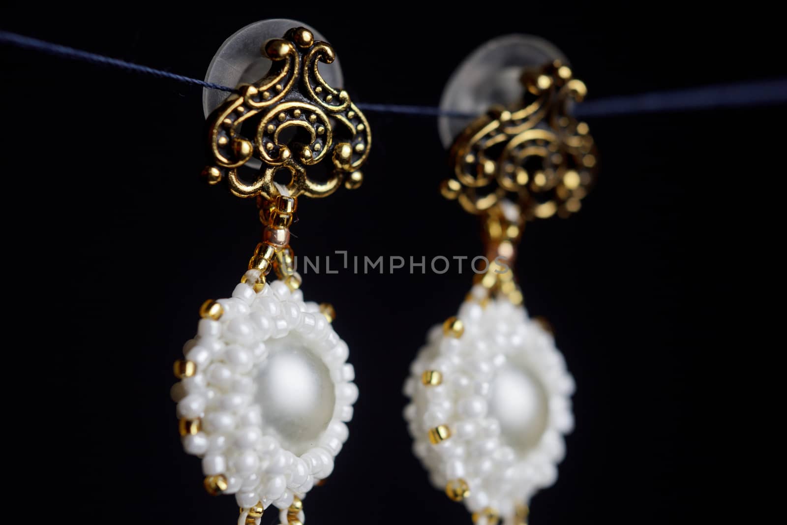 handmade jewelry made of beads in macro. earrings from white beads. earrings from stones. beautiful ornaments. earrings from white beads. ornaments on a black background