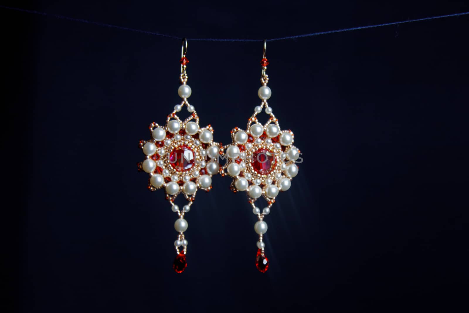 handmade jewelry made of beads in macro. earrings from white beads. earrings from stones. beautiful ornaments. earrings from red beads. ornaments on a black background