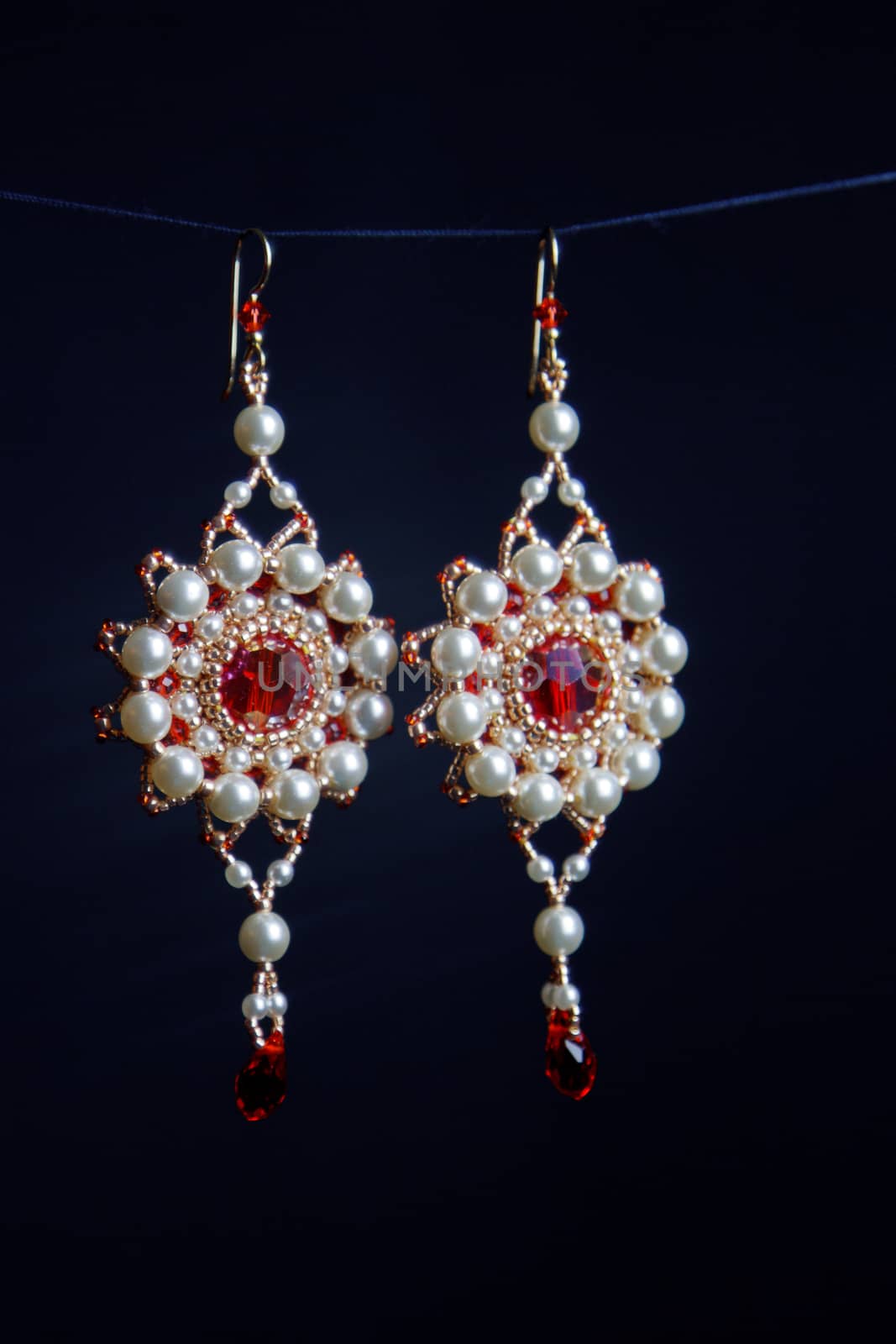 handmade jewelry made of beads in macro. earrings from white beads. earrings from stones. beautiful ornaments. earrings from red beads. ornaments on a black background