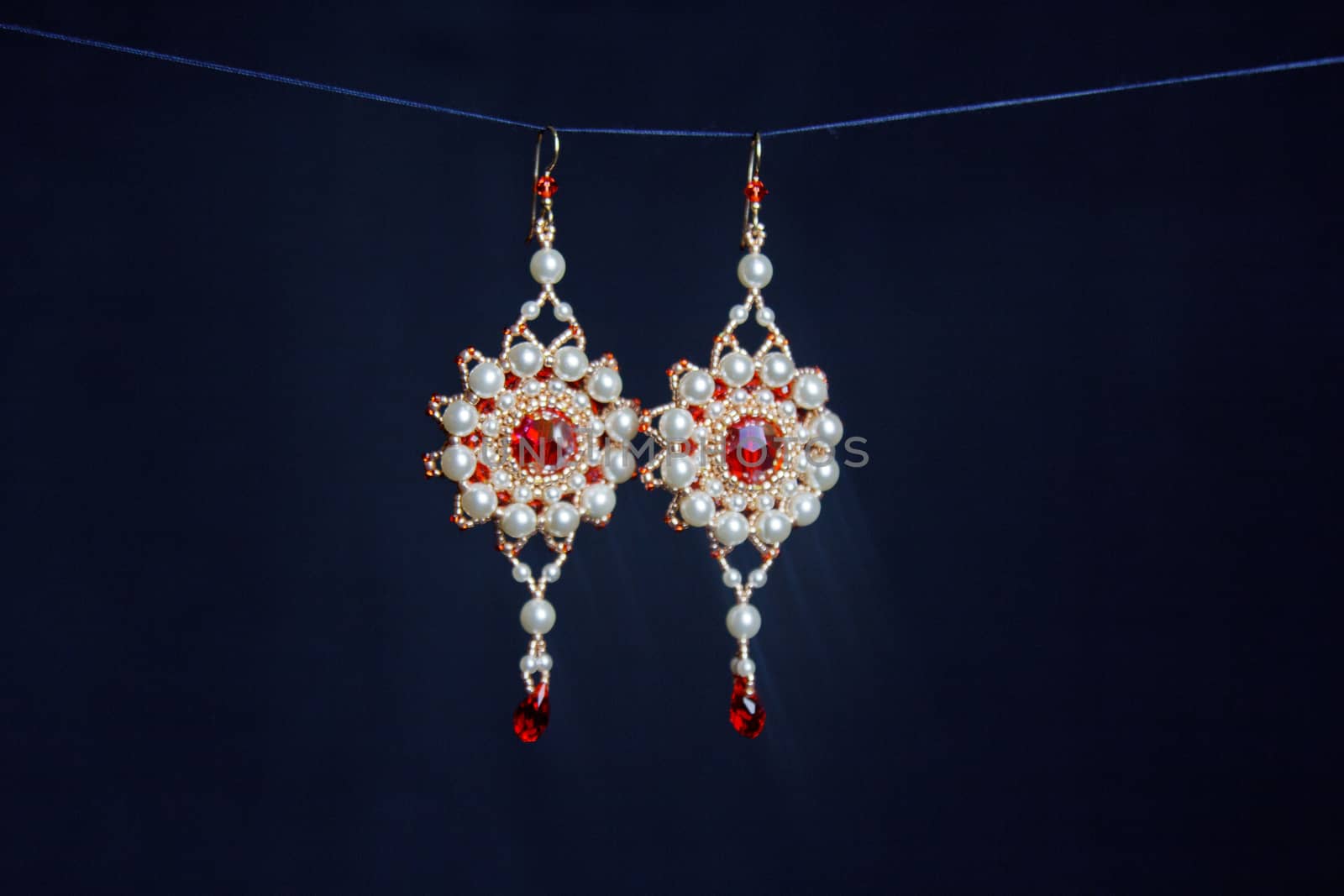 handmade jewelry made of beads in macro. earrings from white beads. earrings from stones. beautiful ornaments. earrings from red beads. ornaments on a black background