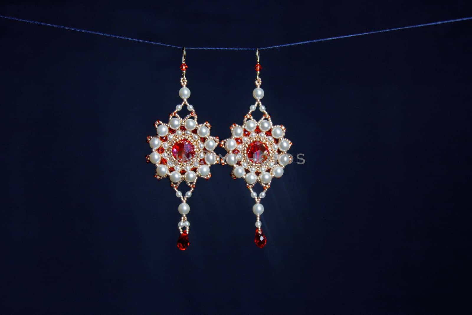 handmade jewelry made of beads in macro. earrings from white beads. earrings from stones. beautiful ornaments. earrings from red beads. ornaments on a black background by yulaphotographer