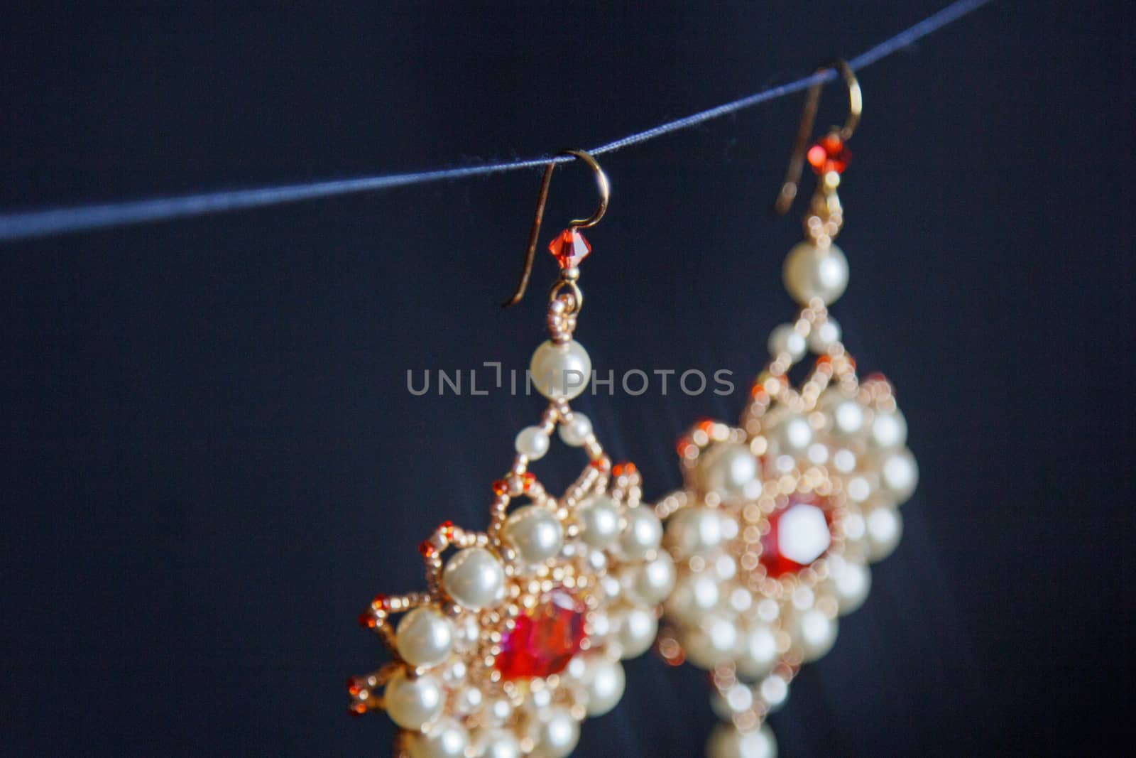 handmade jewelry made of beads in macro. earrings from white beads. earrings from stones. beautiful ornaments. earrings from red beads. ornaments on a black background