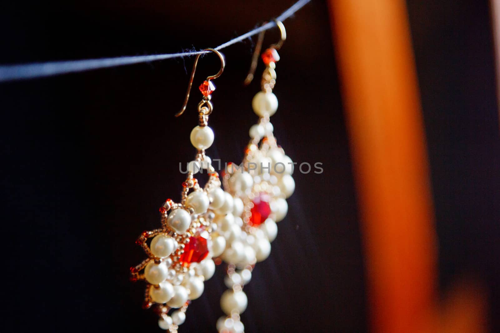 handmade jewelry made of beads in macro. earrings from white beads. earrings from stones. beautiful ornaments. earrings from red beads. ornaments on a black background by yulaphotographer